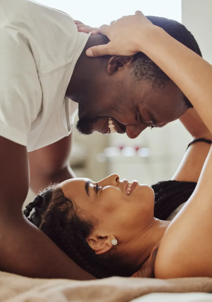 Black couple, love and home bedroom romance while happy and intimate together on bed at home, apartment or hotel.